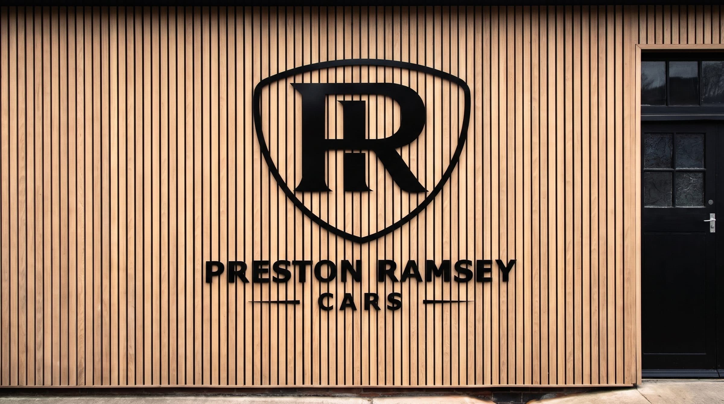 The Preston Ramsey Cars sign on the oak cladding at Randol House